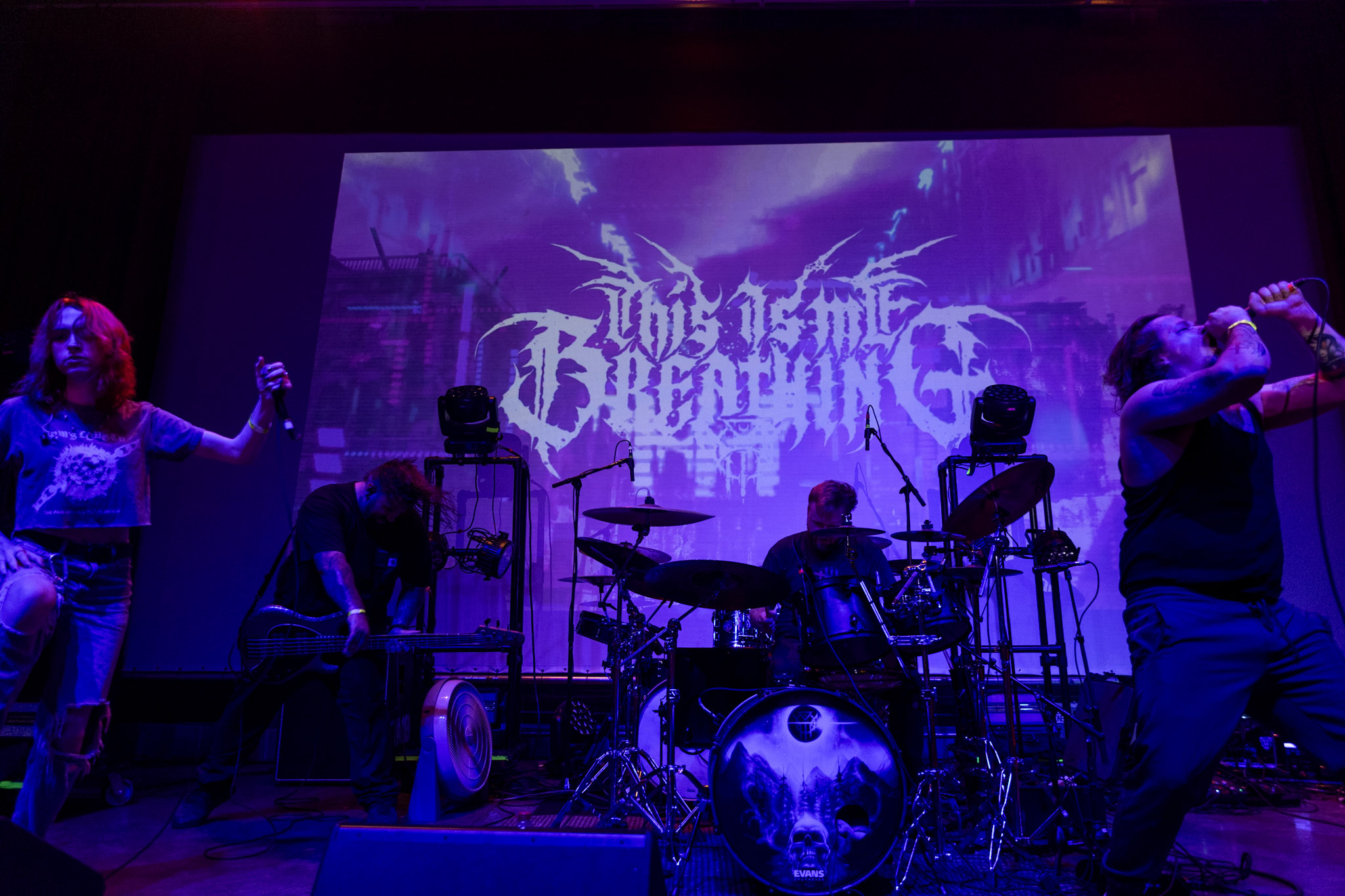 This Is Me Breathing performing beneath purple lighting and their stage logo