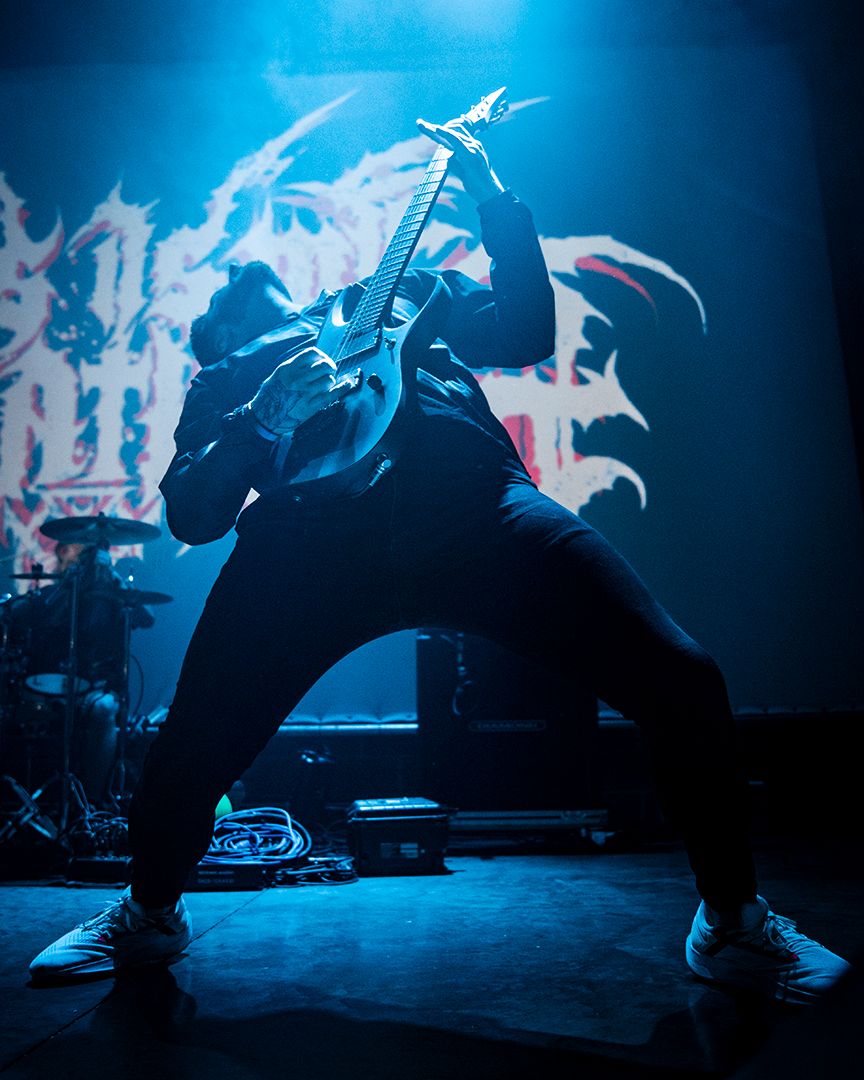 Guitarist performing live under blue stage lighting