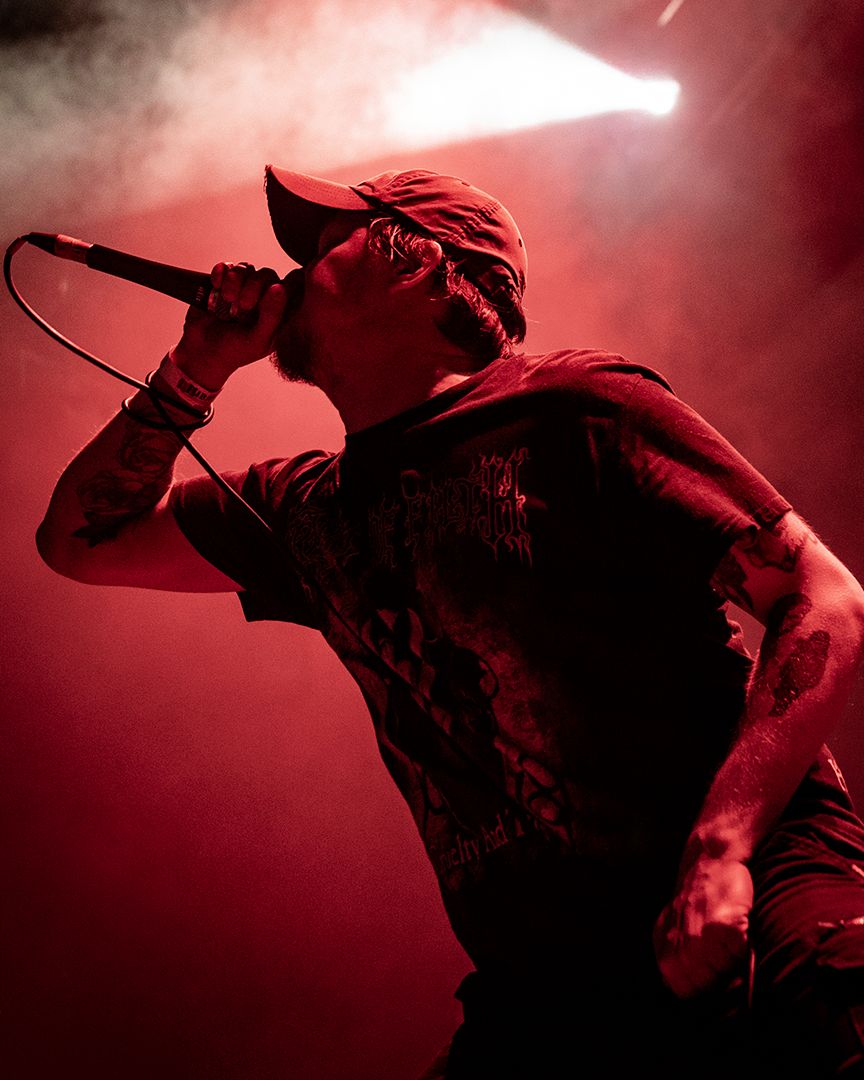 Vocalist performing under red stage lighting